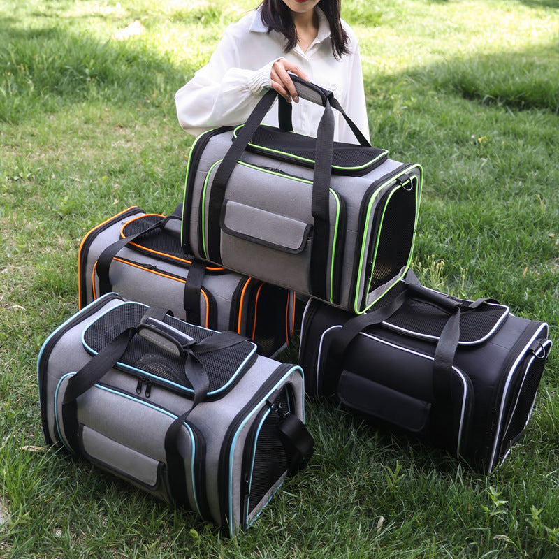 Three pet carrier bags in gray, black, and orange are displayed on a green grass lawn, with a woman in a white shirt holding one of the gray bags.